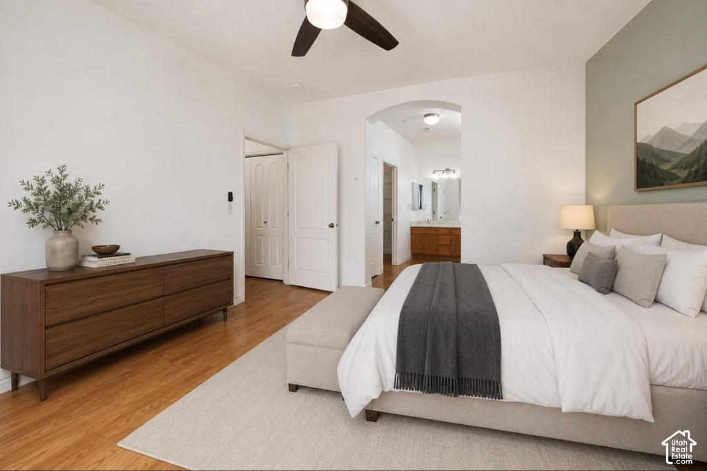 Spacious bedroom featuring wood-finish flooring, a contemporary ceiling fan, and a light-colored accent wall