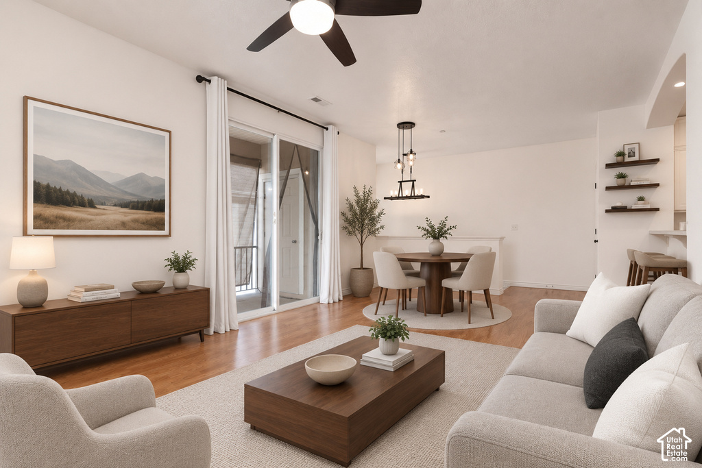 Open-concept living space with wood-finish flooring, a contemporary ceiling fan, and sliding glass doors to a private balcony