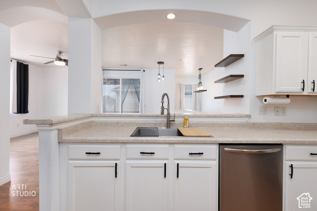 Kitchen featuring white cabinetry with black hardware, an integrated sink with a gooseneck faucet, light-toned countertops, and a stainless steel dishwasher