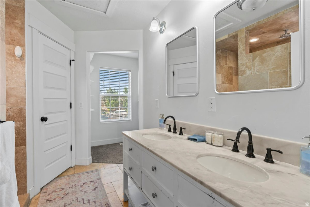 Double vanity with stone countertop and integrated sinks, brushed bronze hardware, and framed mirrors