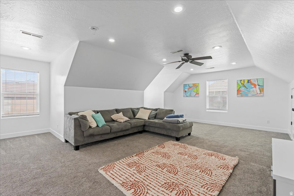 Spacious room featuring sloped ceilings, recessed lighting, and soft gray carpeting