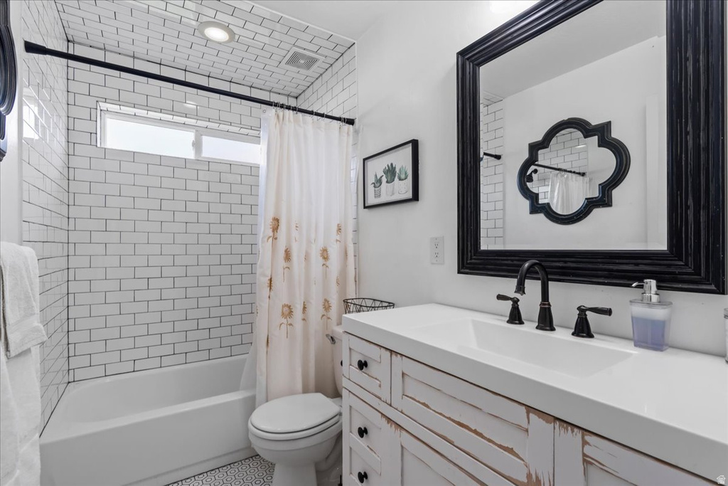 Bathroom featuring white subway tile surround, white bathtub, white vanity with black hardware, black framed mirror, and black plumbing fixtures