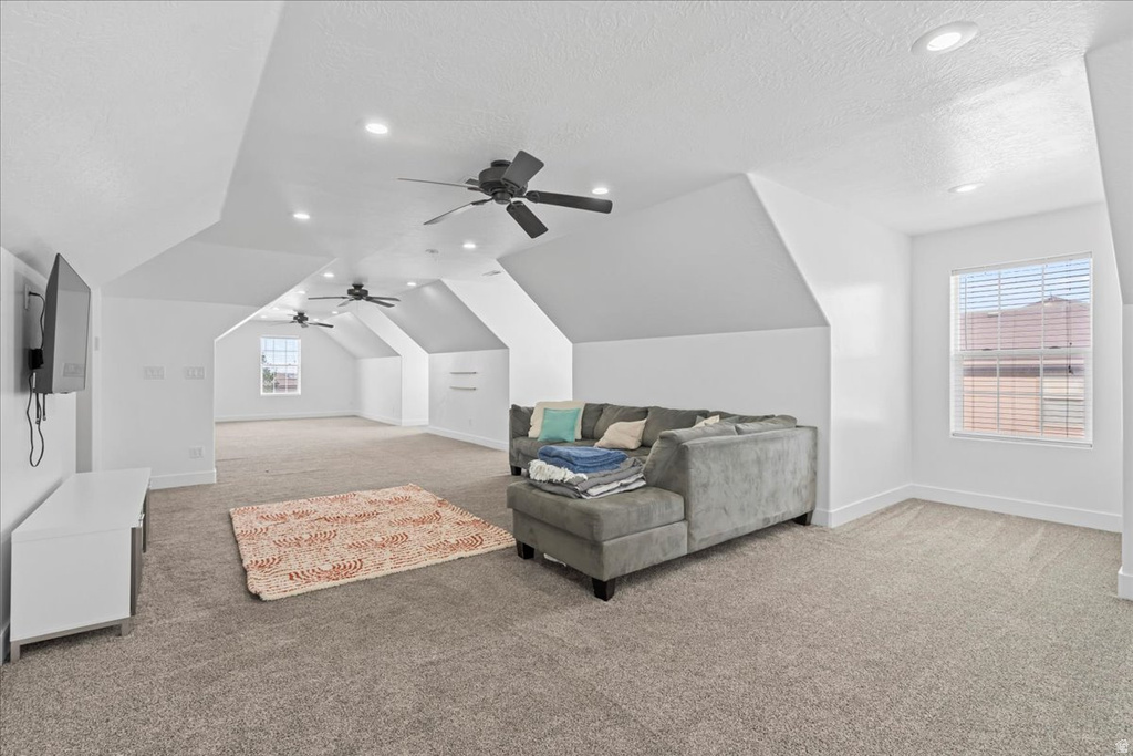 Spacious bonus room featuring vaulted ceilings, recessed lighting, multiple ceiling fans, neutral carpeting, and abundant natural light from multiple windows