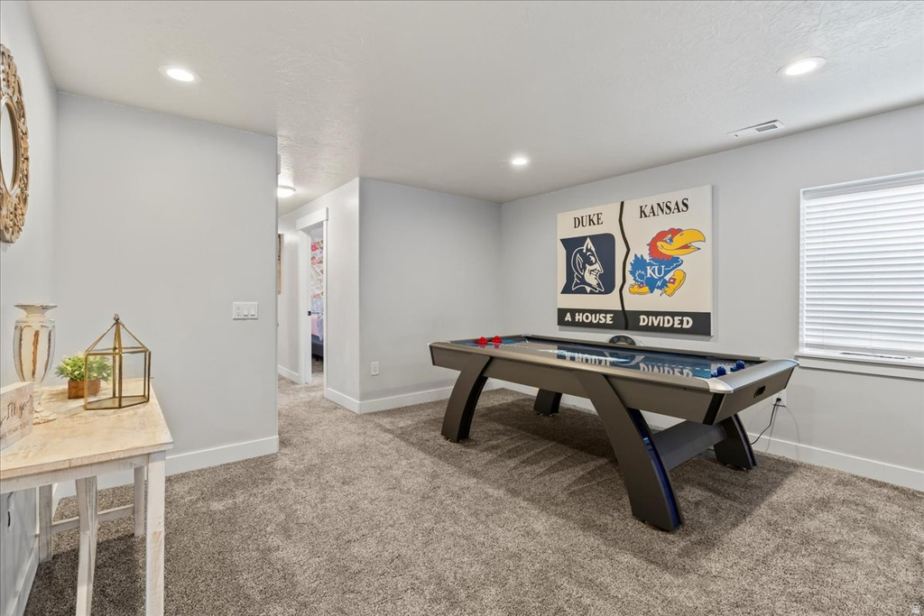 Recreation room featuring plush carpeting, recessed lighting, and a window with blinds