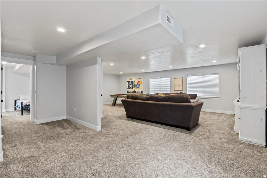 Spacious lower-level area featuring light gray walls, plush gray carpeting, and recessed lighting