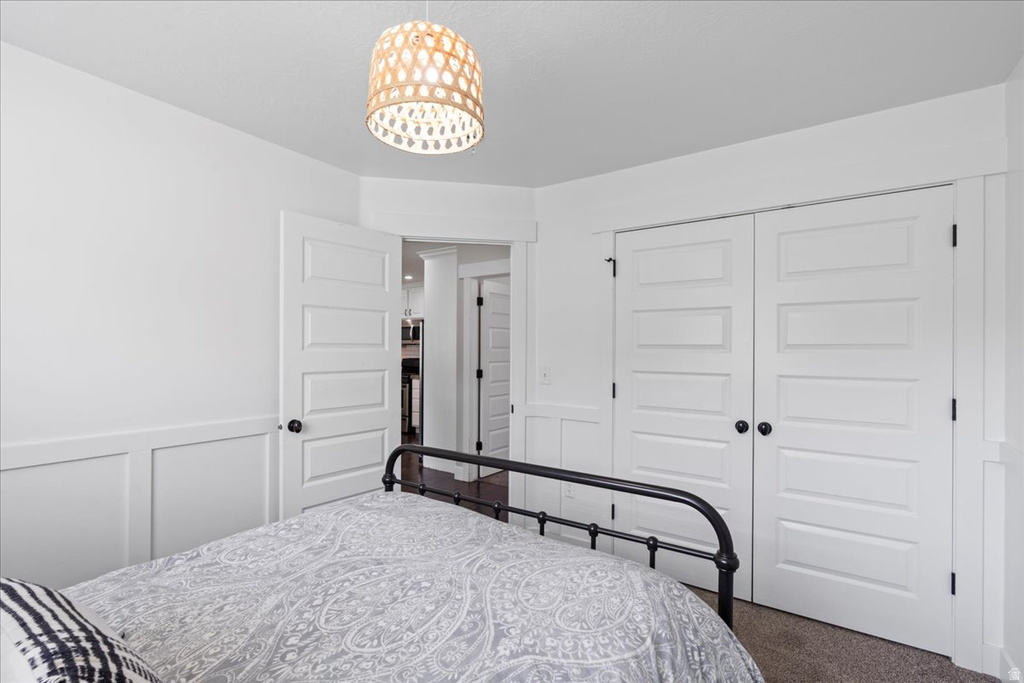 White paneled bedroom featuring wainscoting, wood-finish flooring, and a decorative pendant light fixture
