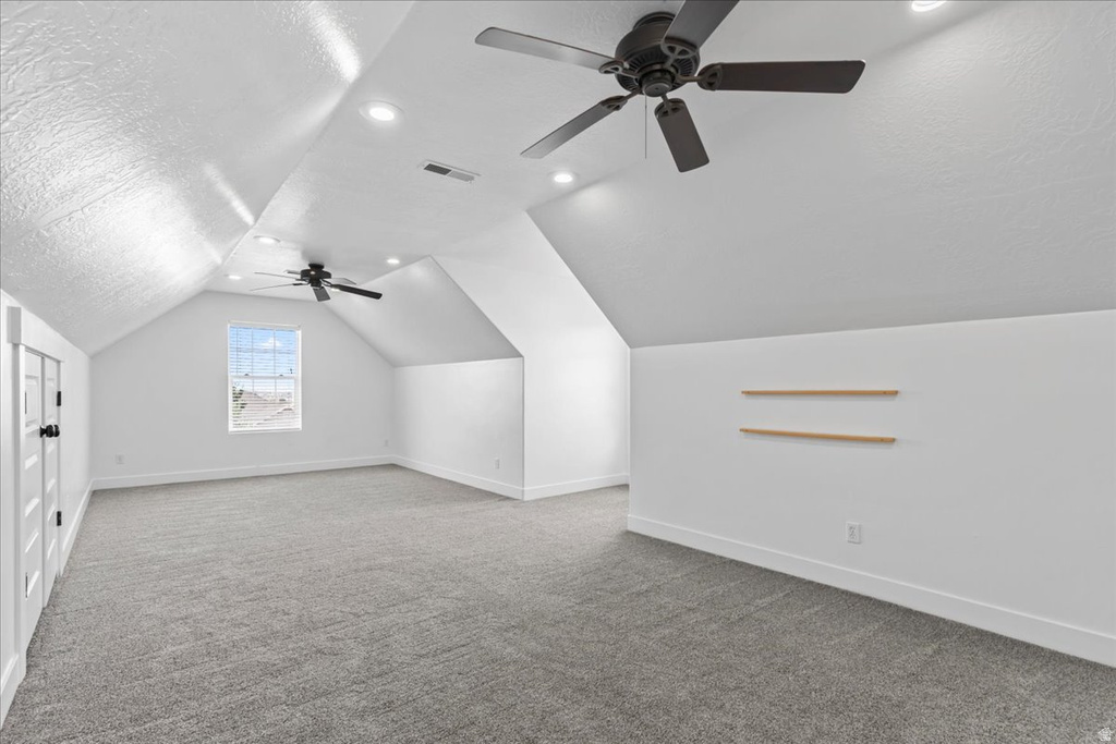 Spacious room featuring vaulted ceilings, recessed lighting, and two ceiling fans