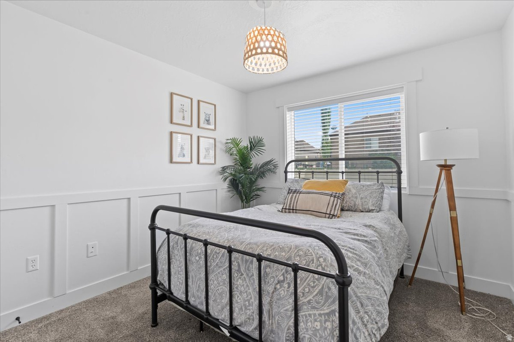 Bedroom featuring a large window, board and batten wall detailing, overhead lighting fixture, and carpet flooring