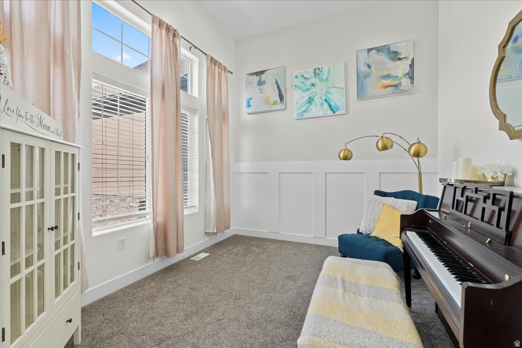 Spacious room featuring high ceilings, tall windows with blinds, and white board and batten wall detailing