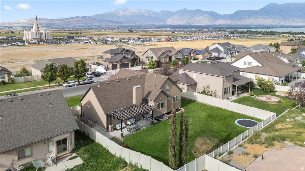 Expansive backyard featuring a manicured lawn, a built-in fire pit area, and a covered patio with a slatted pergola