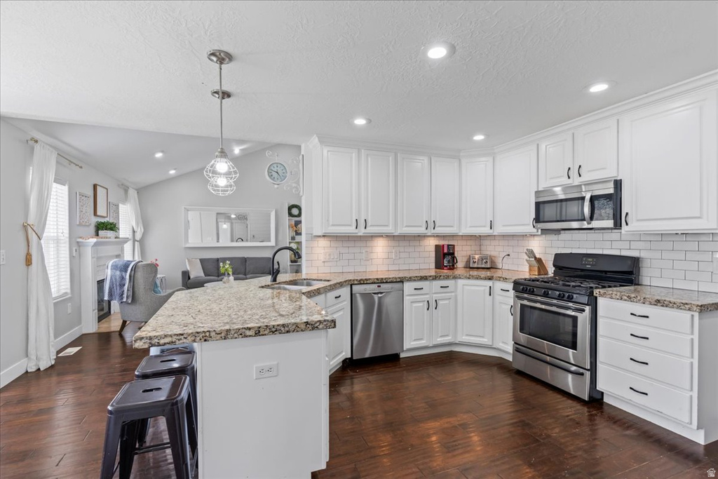 Spacious kitchen featuring white cabinetry, stainless steel appliances, granite countertops, and wood-finish flooring