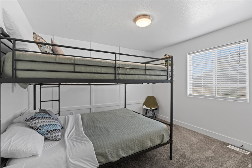 Carpeted room featuring a large window with blinds and a ceiling-mounted light fixture