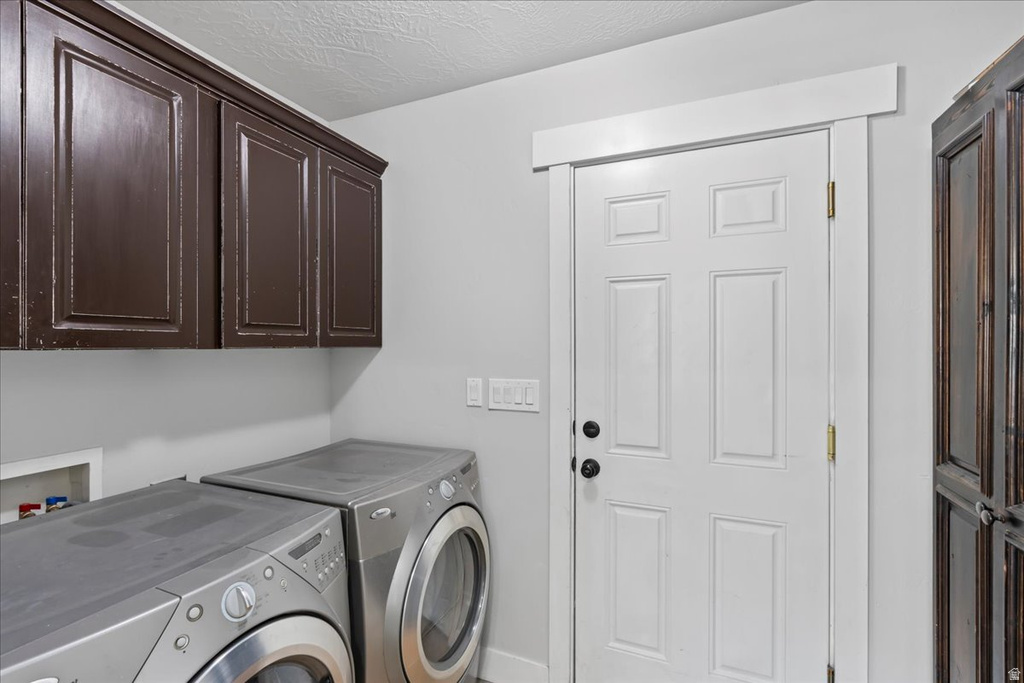 Laundry area featuring brown upper cabinetry, a paneled white door with black hardware, and an additional storage cabinet