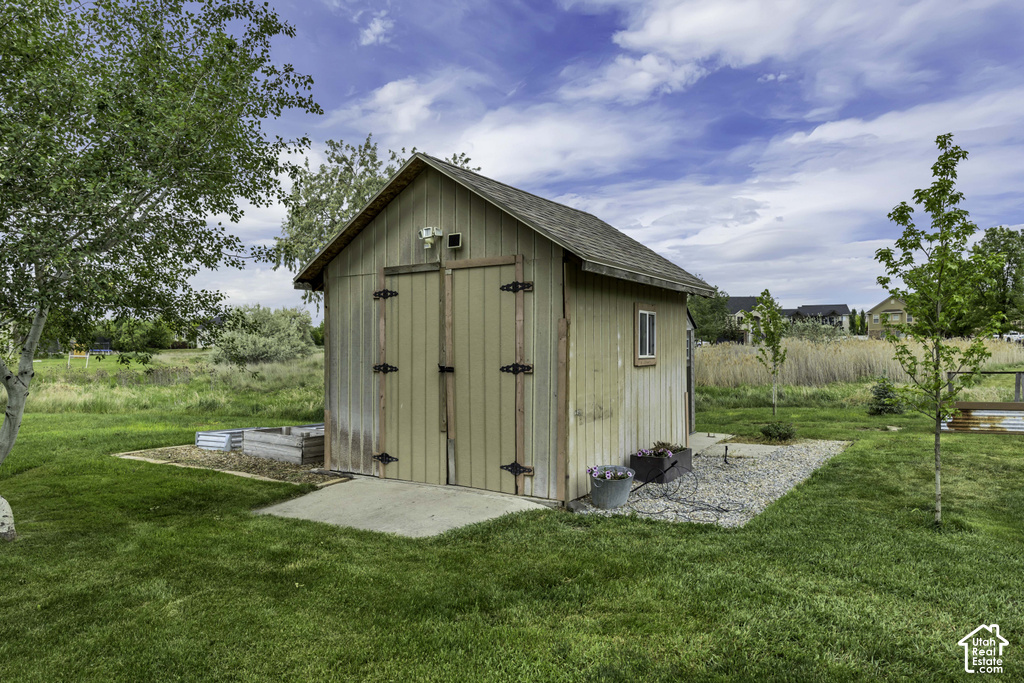 Detached shed featuring board-and-batten siding, double doors with strap hinges, and a shingle roof