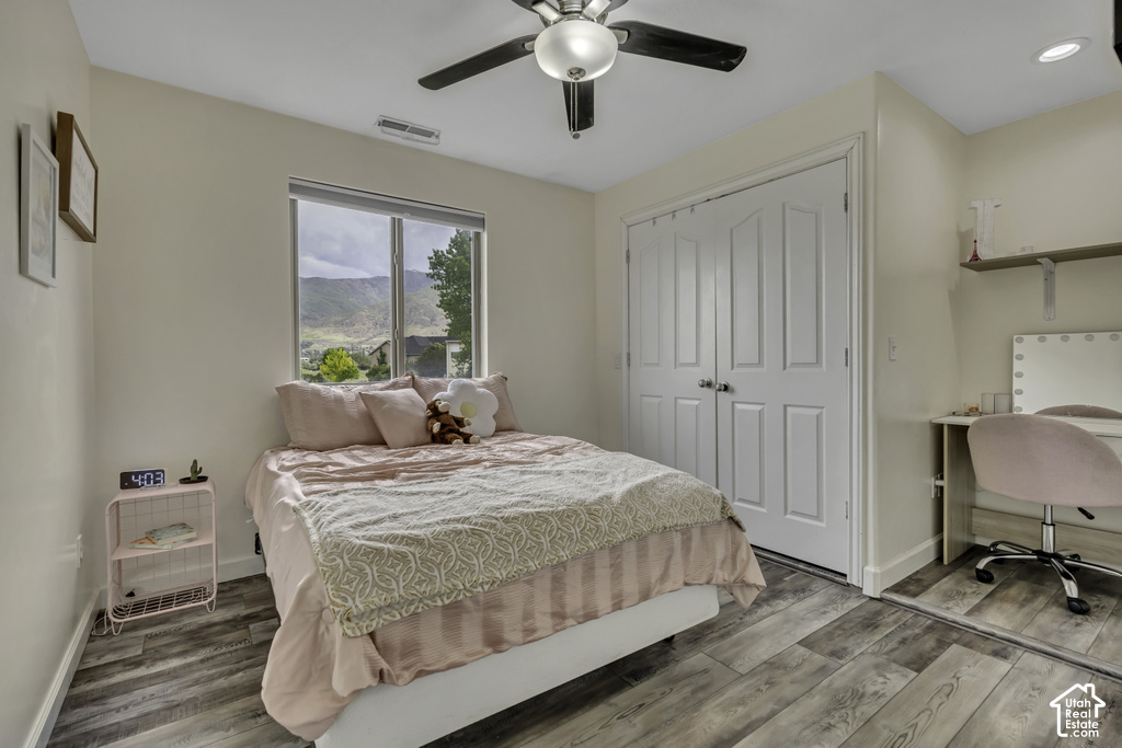 Interior space featuring wood-finish flooring, a window offering mountain scenery, a ceiling fan with integrated lighting, and double bi-fold closet doors