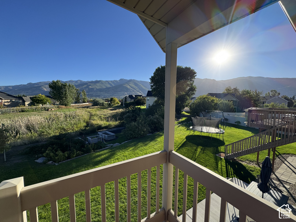Expansive backyard with a manicured lawn, multi-level wood deck, and mountain backdrop