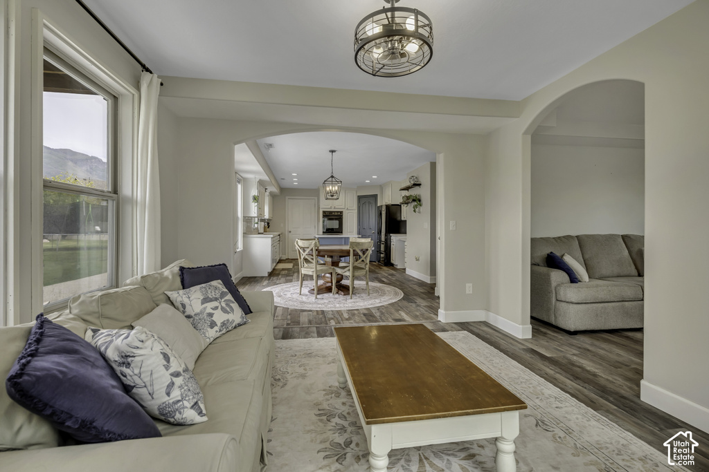 Open-concept living space featuring wood-finish flooring, a contemporary ceiling fan, and arched doorways