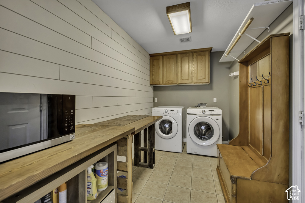 Laundry area featuring an accent shiplap wall, tile flooring, and overhead cabinetry