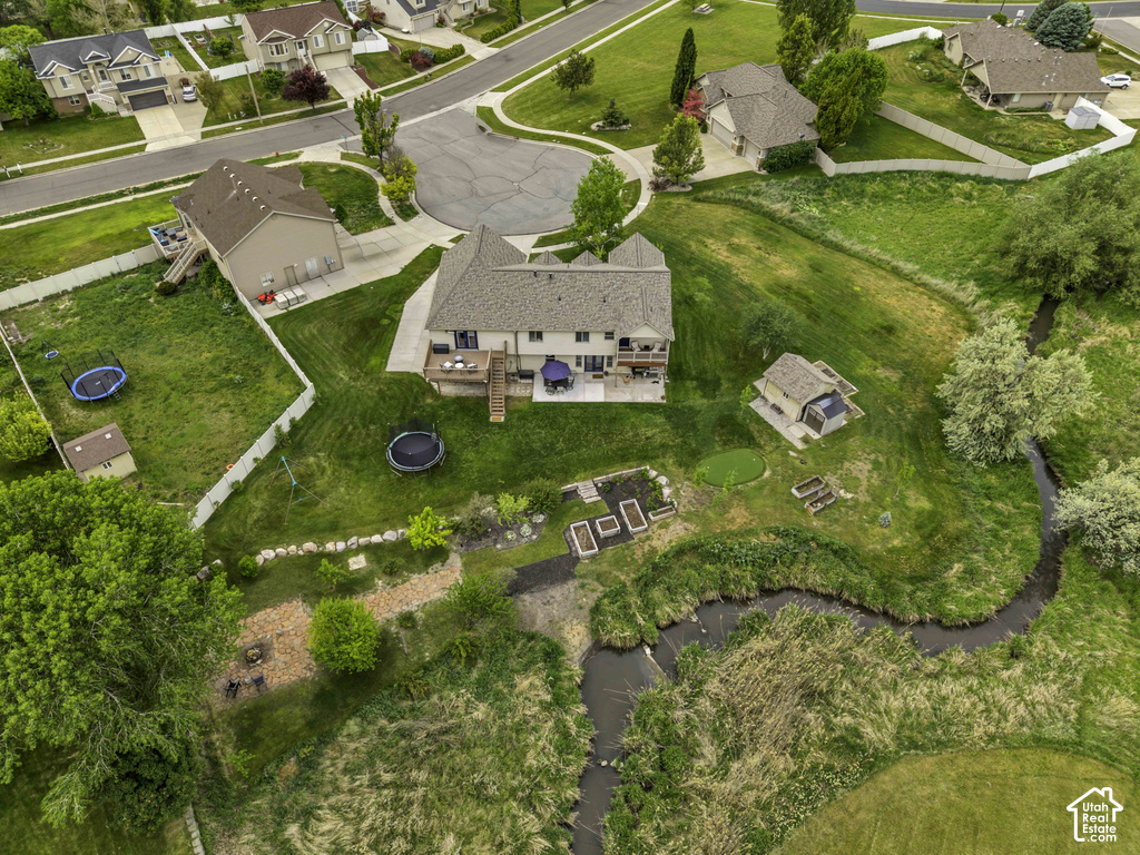 Expansive residential property featuring a winding creek, dedicated outbuilding, multiple raised garden beds, and a stone-edged fire pit area