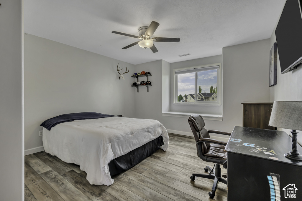 Room featuring wood-finish flooring, a ceiling fan with integrated lighting, and a window with white trim