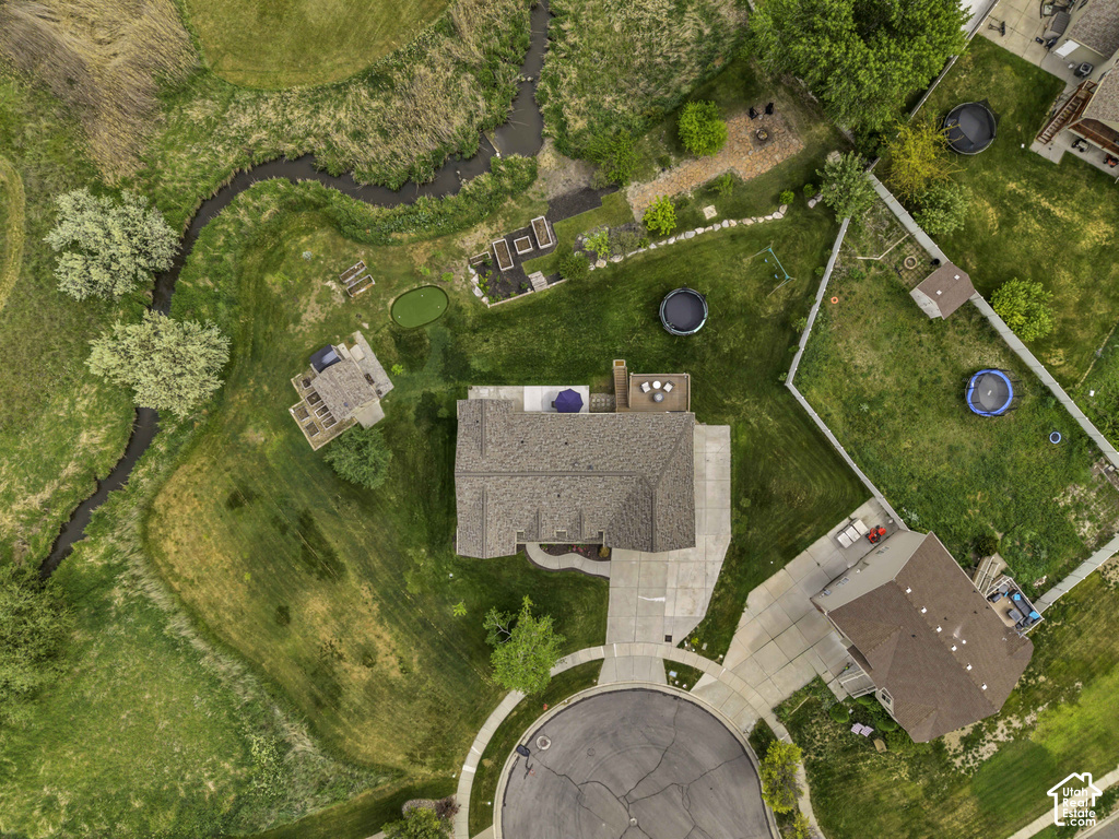 Expansive property featuring a cul-de-sac location, paved driveway, large main residence with a brown shingle roof, a secondary structure with a deck, and an elongated stream bordering the property
