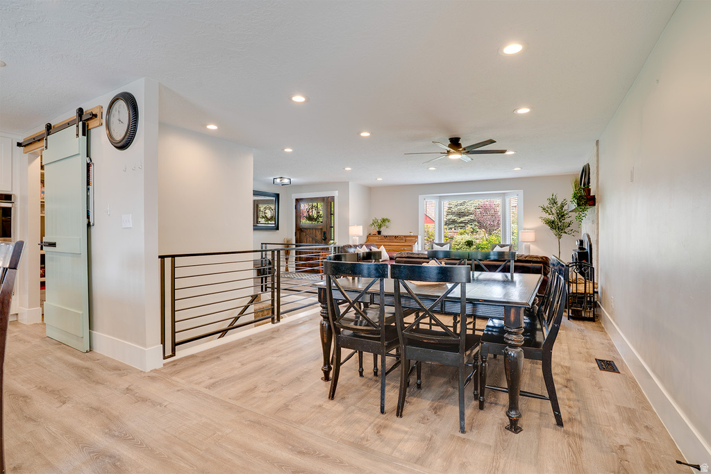 Open-concept dining area featuring wood-finish flooring, recessed lighting, and a barn door entry