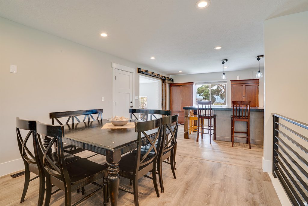 Open-concept dining area with wood-finish flooring, recessed lighting, and a sliding barn door feature