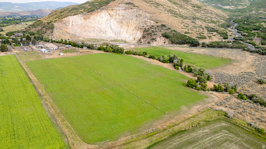 Expansive green fields bordered by natural terrain and distant mountains