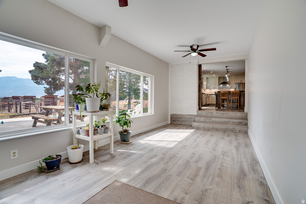 Spacious living area featuring large windows, wood-finish flooring, and a ceiling fan