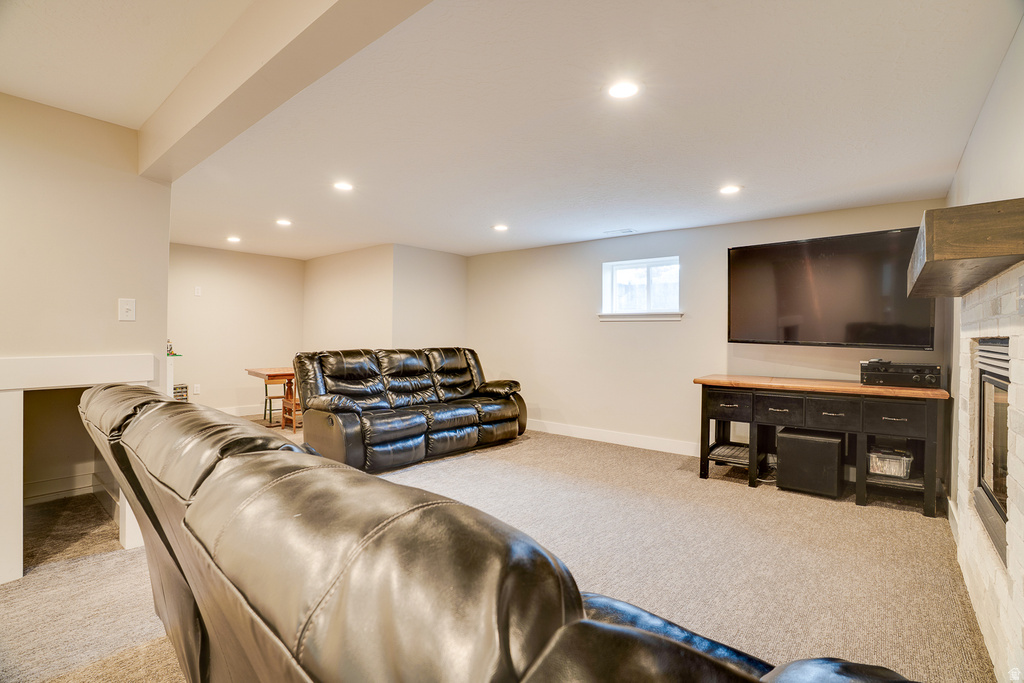 Spacious recreation room featuring recessed lighting, light-colored carpeting, a window, and a fireplace with a stone surround and wood mantel