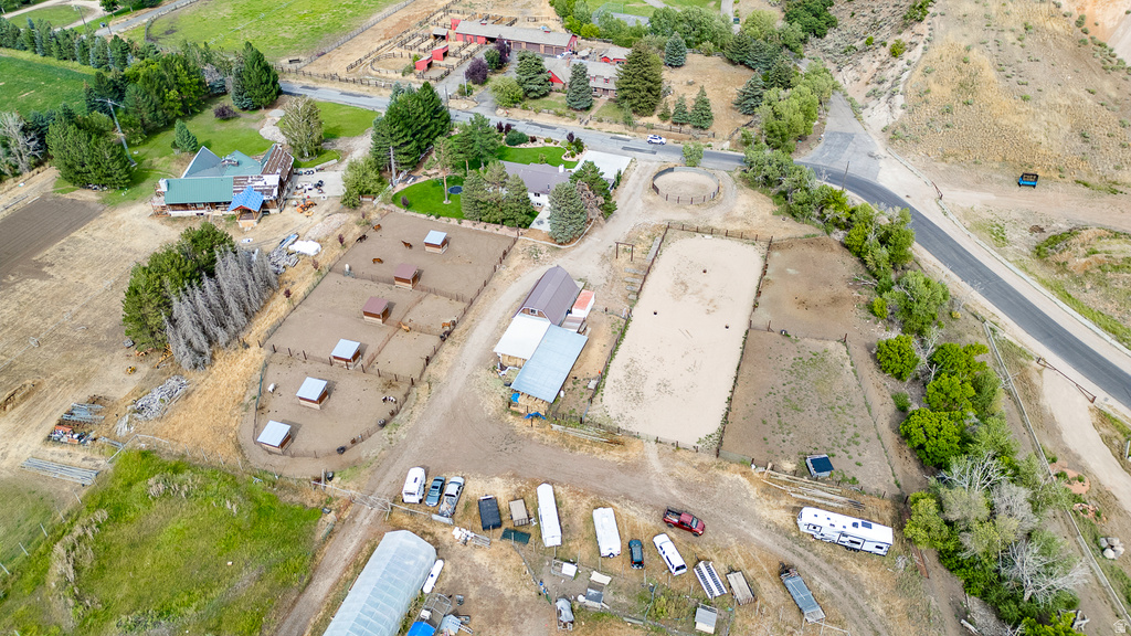 Expansive rural property featuring multiple fenced enclosures, a large riding arena, and a main residence with a green roof