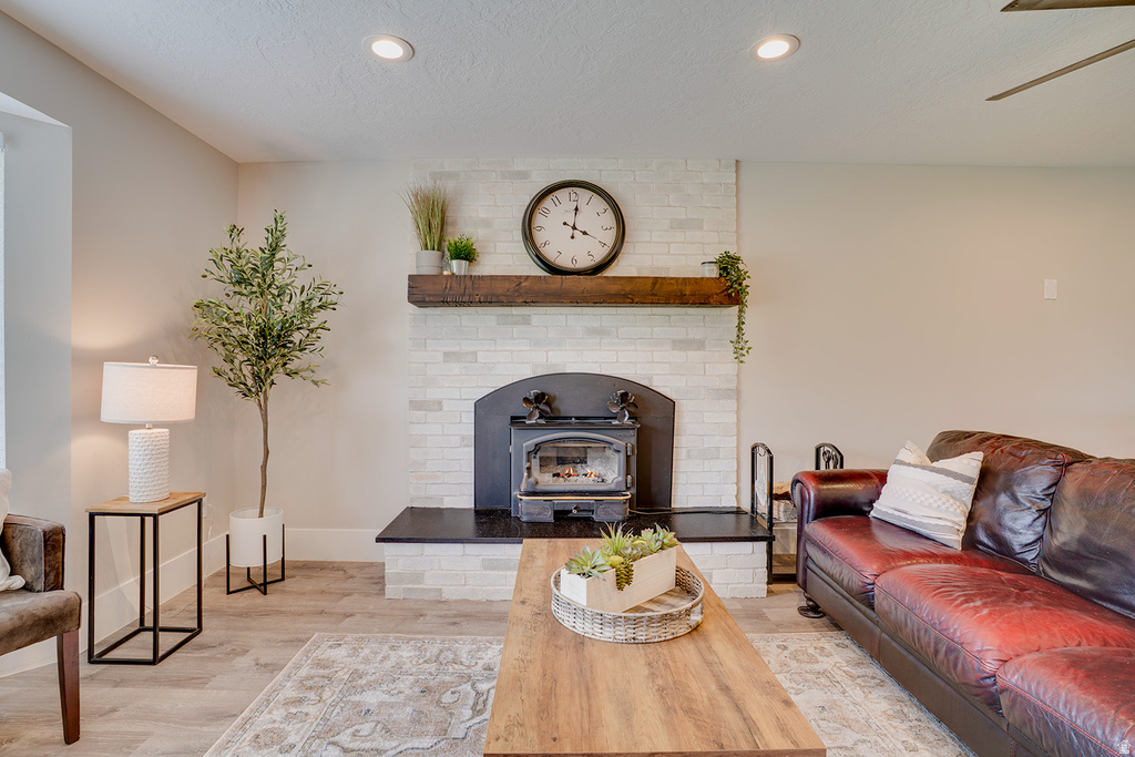 Living space featuring wood-finish flooring, recessed lighting, and a white brick fireplace with a dark wood mantel and black hearth