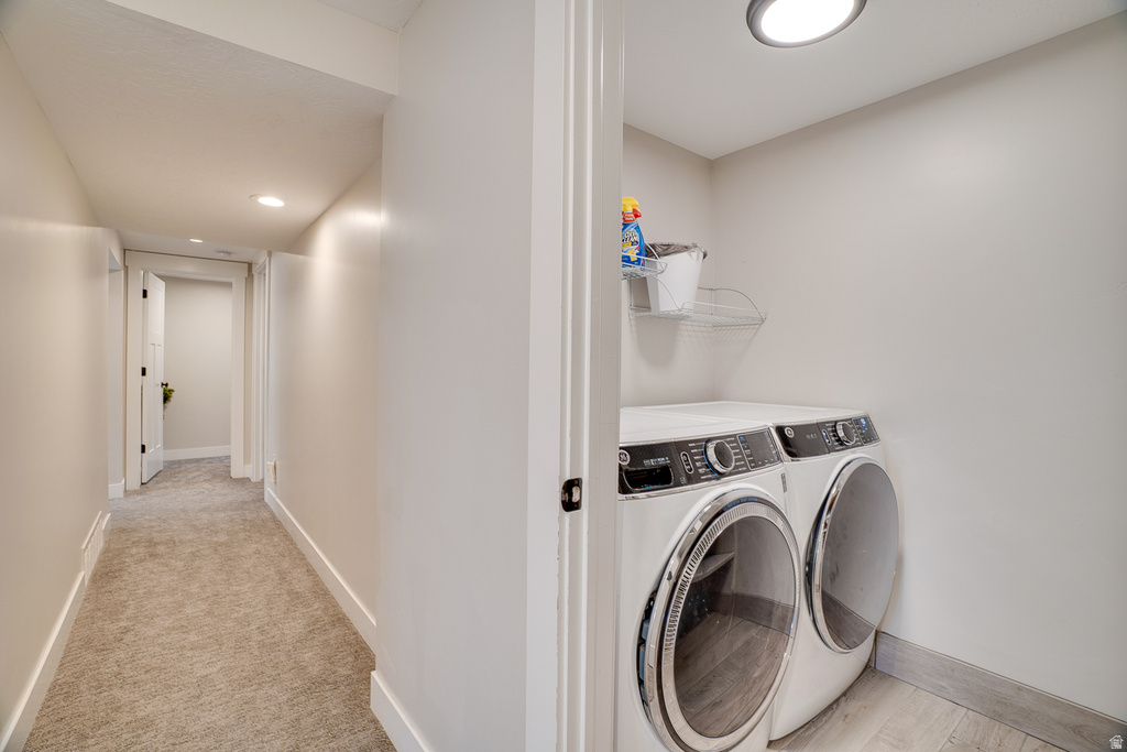 Dedicated laundry area featuring a front-loading washer and dryer, recessed lighting, and wood-finish flooring