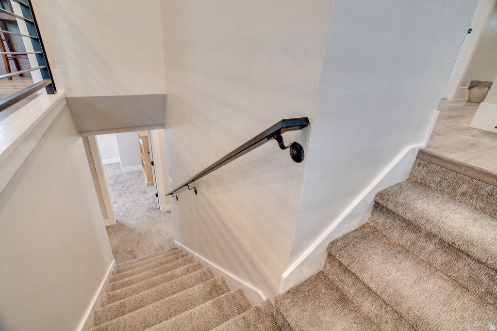 Carpeted staircase with a black metal handrail and white baseboards