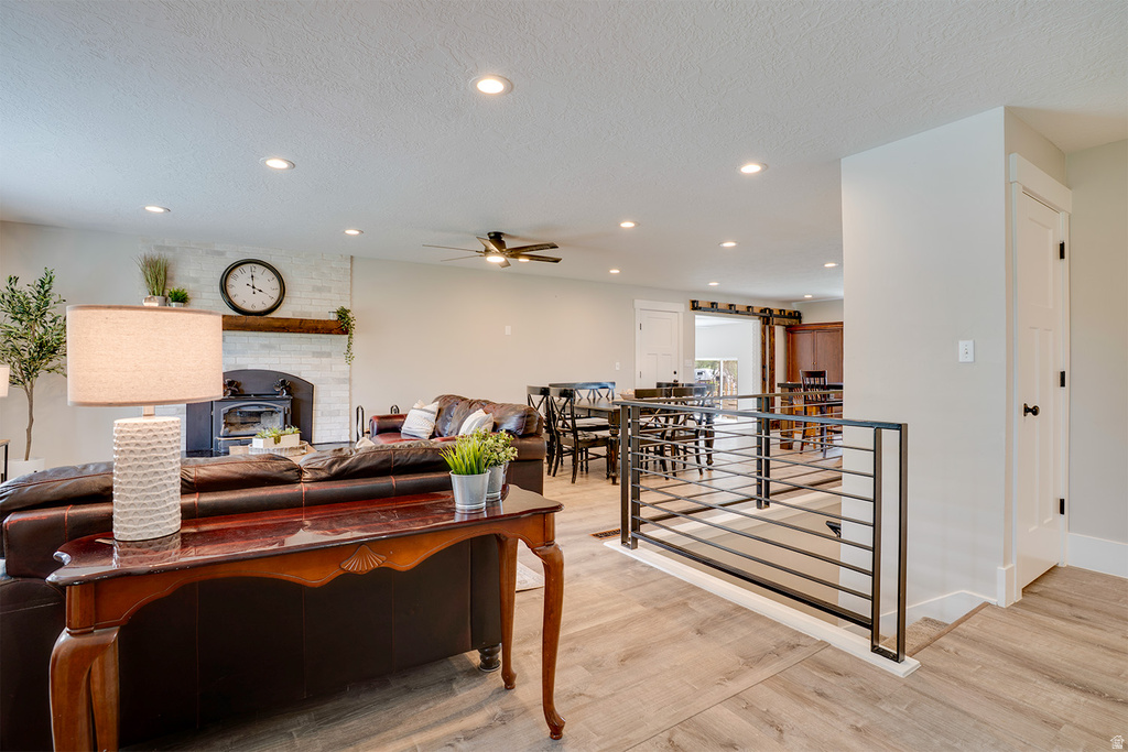 Open-concept living space featuring wood-finish flooring, recessed lighting, and a modern fireplace with a white brick surround and wood mantel