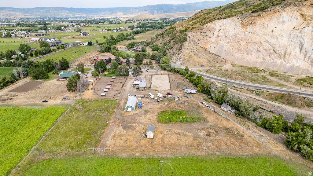 Expansive property featuring multiple structures, cultivated fields, and a hillside backdrop