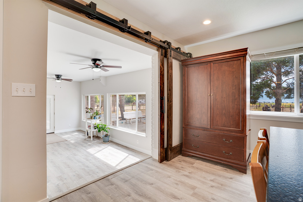 Light wood-finish flooring extending into an adjacent room, highlighted by a black barn door hardware system