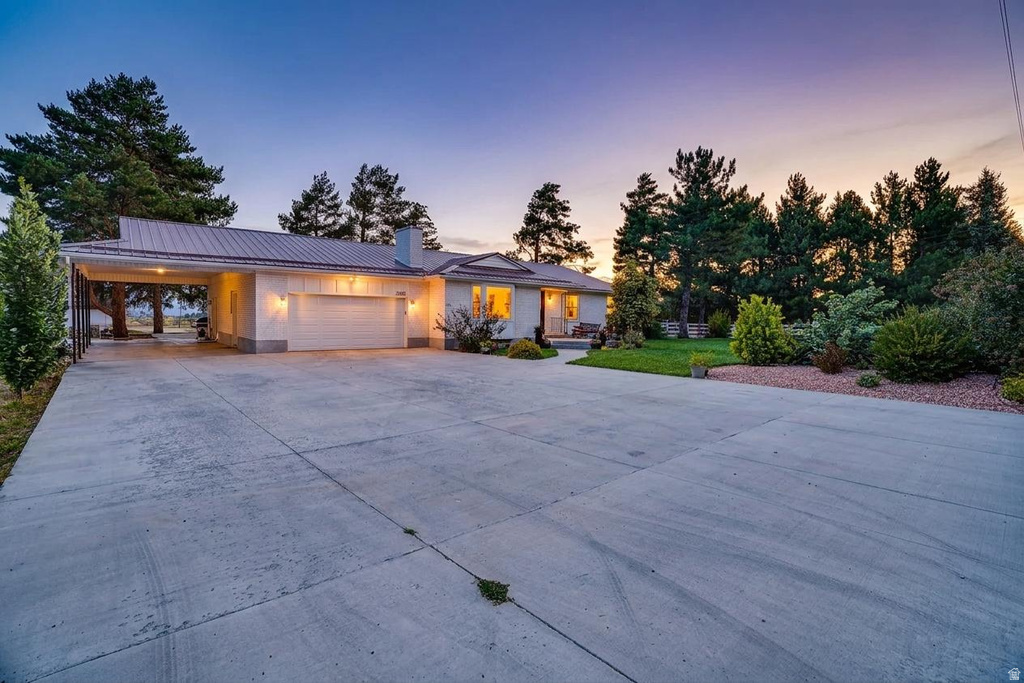 Expansive concrete driveway leading to a white exterior home with an attached two-car garage and a covered carport