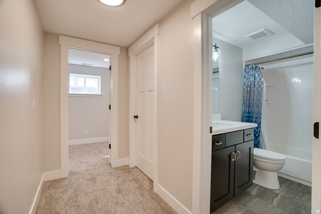 Bathroom featuring a dark wood-finish vanity with a white countertop, a white toilet, and a white bathtub with an overhead shower