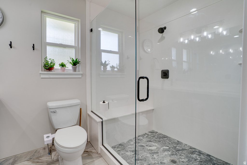 Glass-enclosed shower featuring a built-in bench and dark-toned floor tile