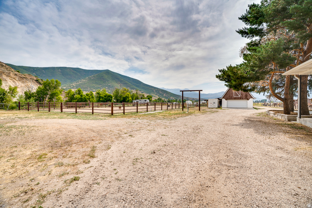 Expansive gravel drive encompassing a fenced-in riding arena and a rustic barn with a white garage door