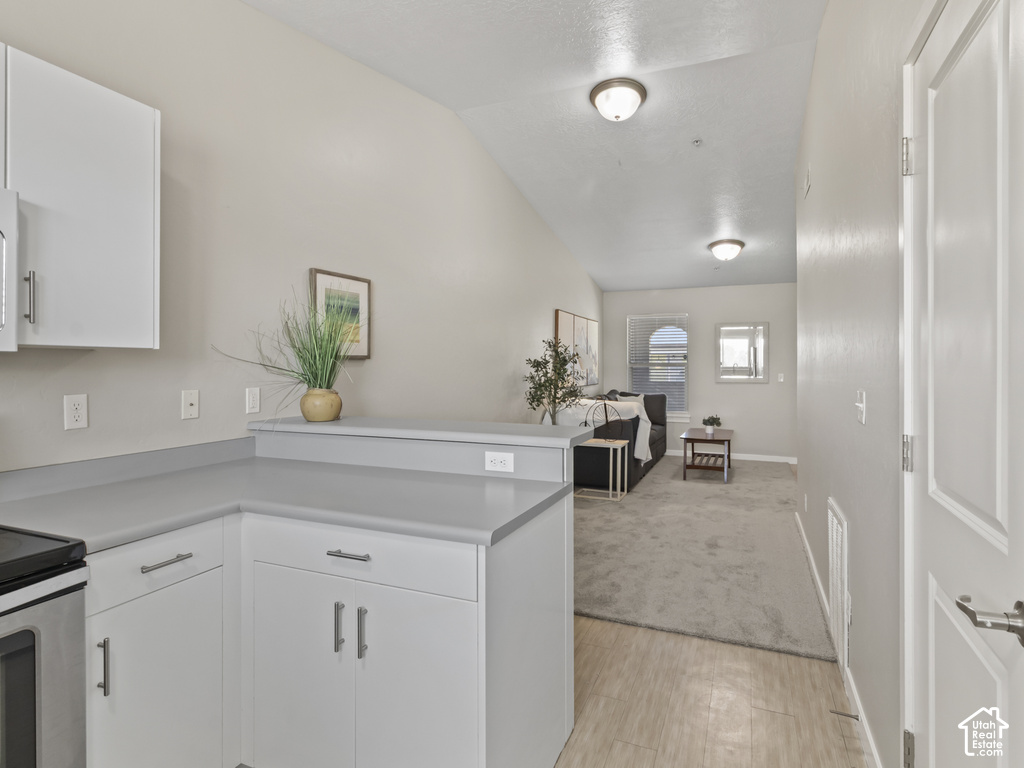 Kitchen area featuring white cabinetry with silver hardware, light gray countertops, and wood-finish flooring