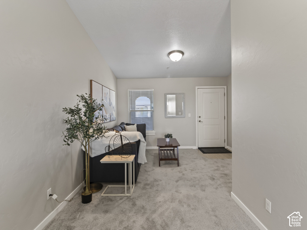 Living area featuring light gray wall paint, gray carpeting, a window with horizontal blinds, and a white paneled entry door