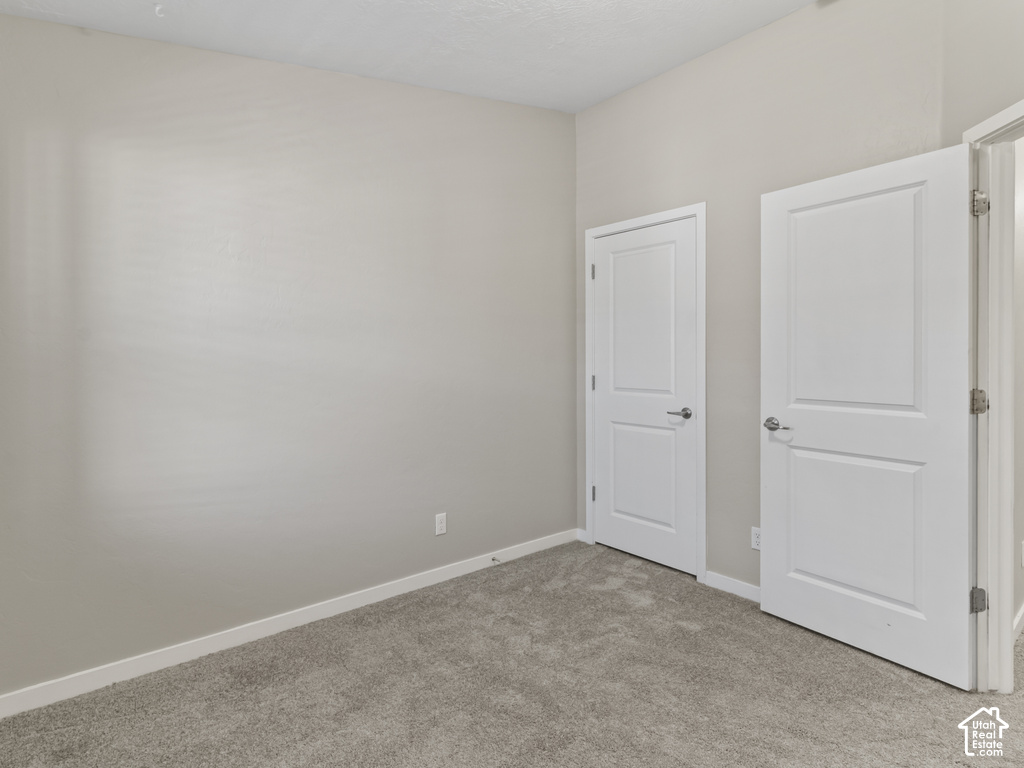 Wall-to-wall carpeting in a neutral tone, complemented by light gray wall paint and white baseboards