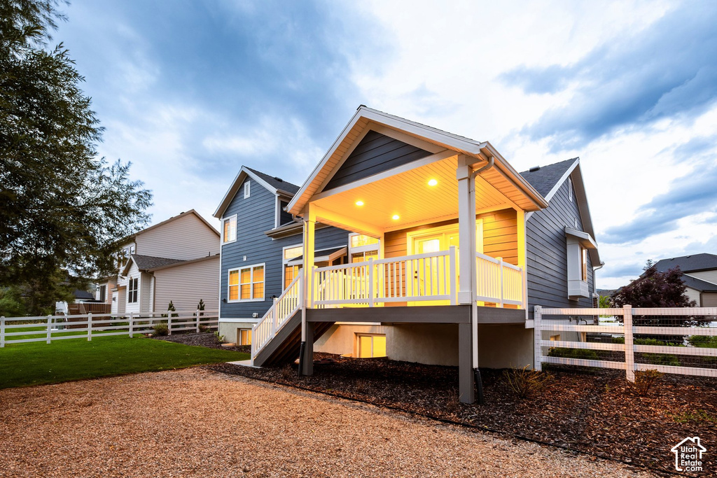 Rear exterior featuring a covered deck with recessed lighting, white railings, and steps to grade