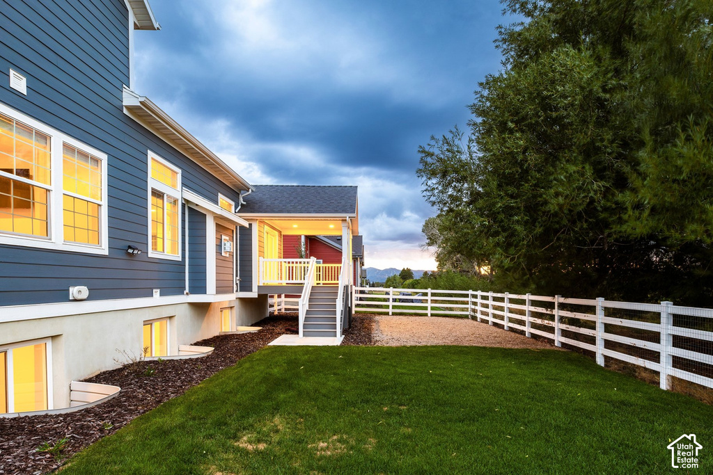 Exterior featuring blue siding and white trim, covered porch with white railings, and a two-tier white fence enclosing a gravel and grass yard