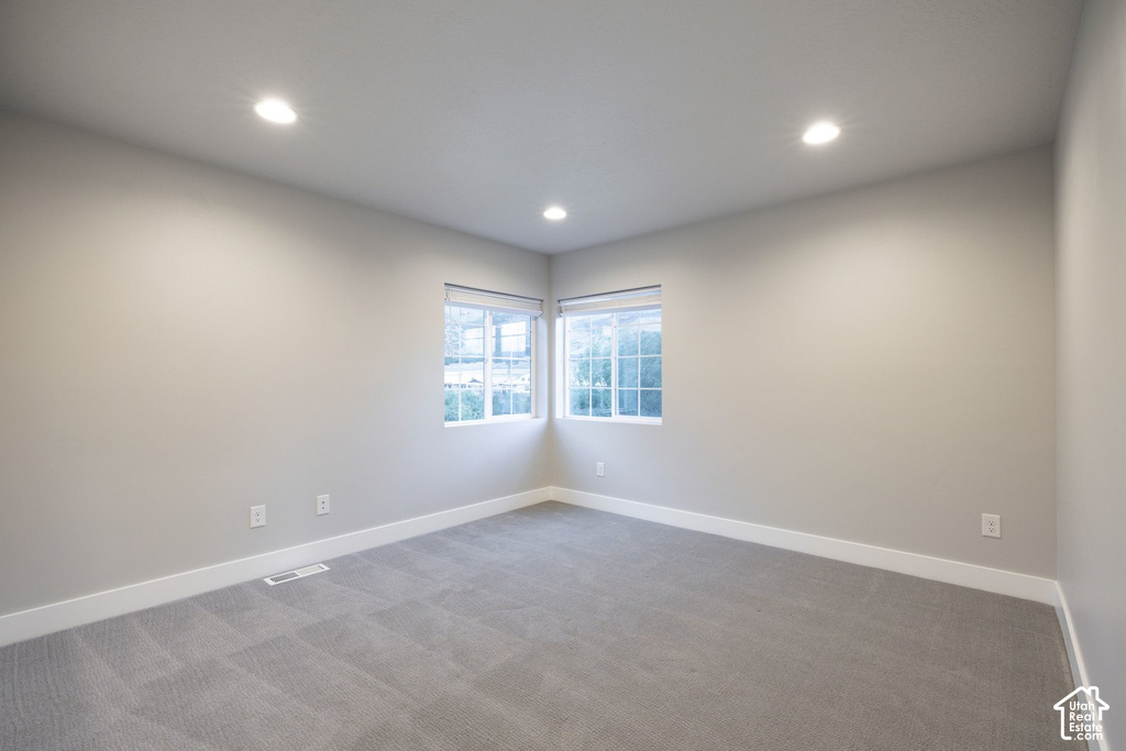 Corner windows providing natural light, recessed lighting, neutral gray wall tones, gray carpet flooring, and white trim