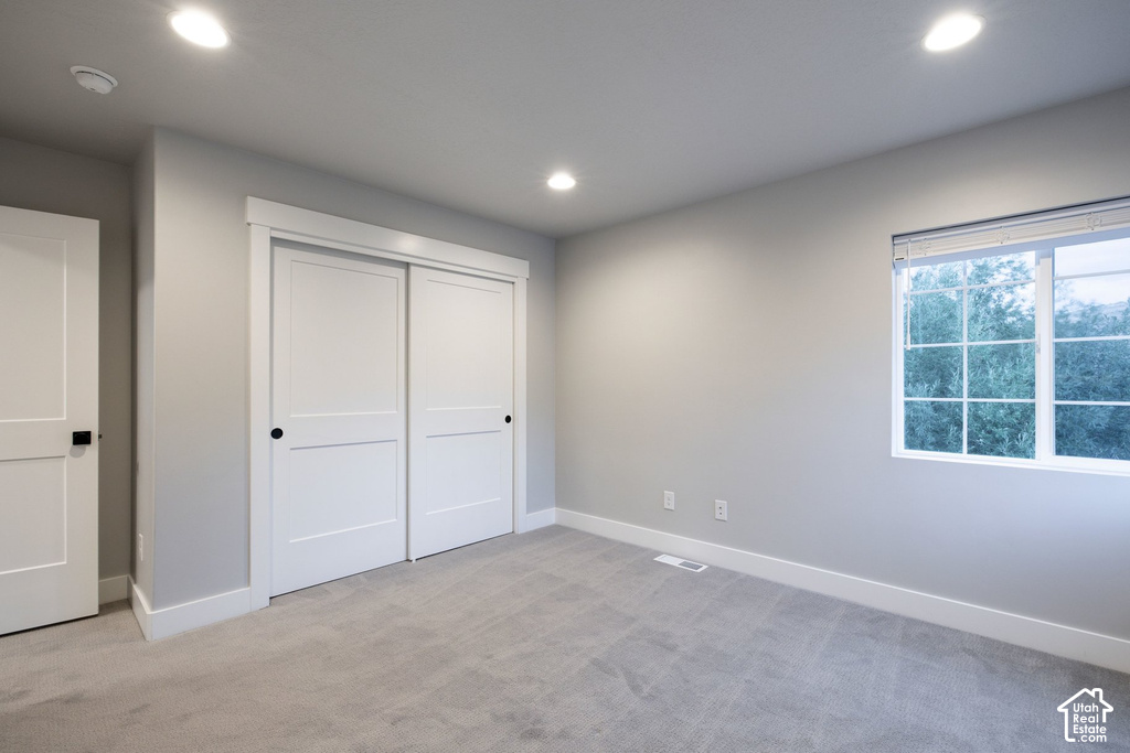 Spacious bedroom featuring dual sliding closet doors with modern hardware, recessed ceiling lighting, large windows with natural light exposure, neutral wall finishes, and carpet flooring throughout