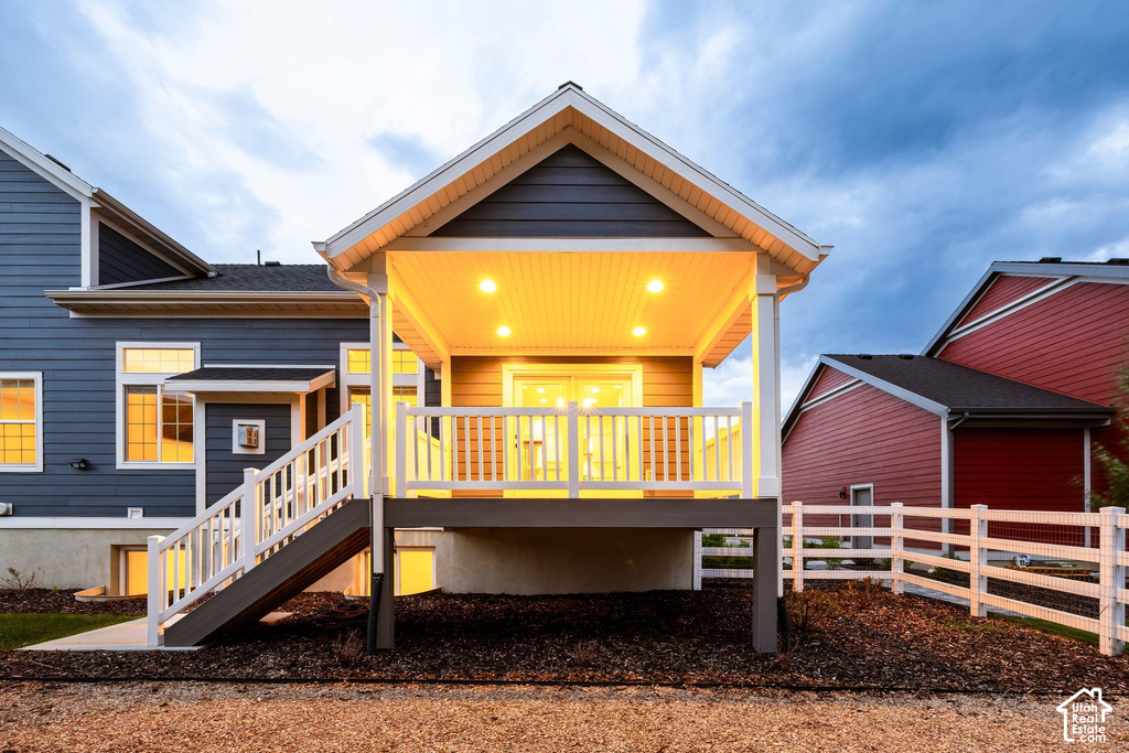 Covered outdoor deck with recessed lighting and white railings, featuring direct access to the interior through a glass door