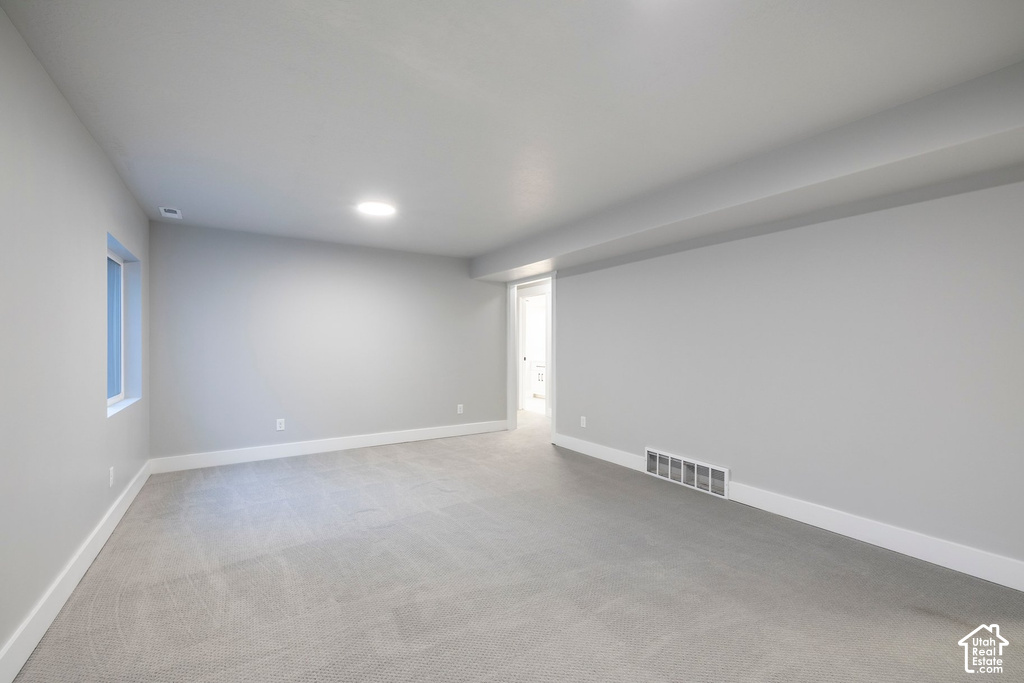 Spacious room featuring light gray walls, plush gray carpeting, a single window, recessed lighting, and white baseboards